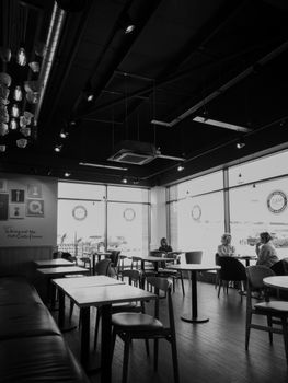 Black and white photo of an urban café interior with tables and customers sitting and talking.
