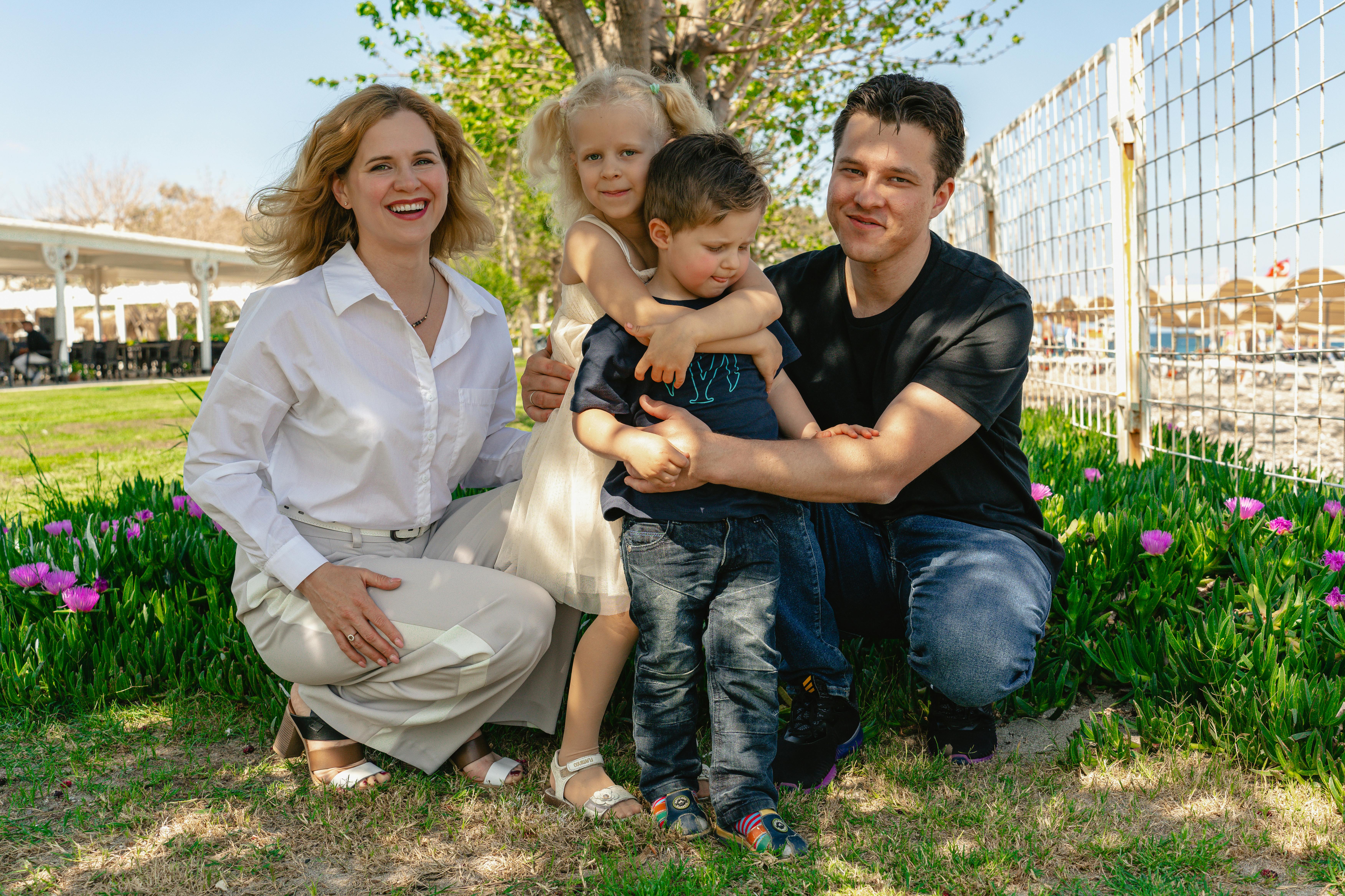 Family of four enjoying a sunny day outdoors in Kemer, smiling and spending quality time together.