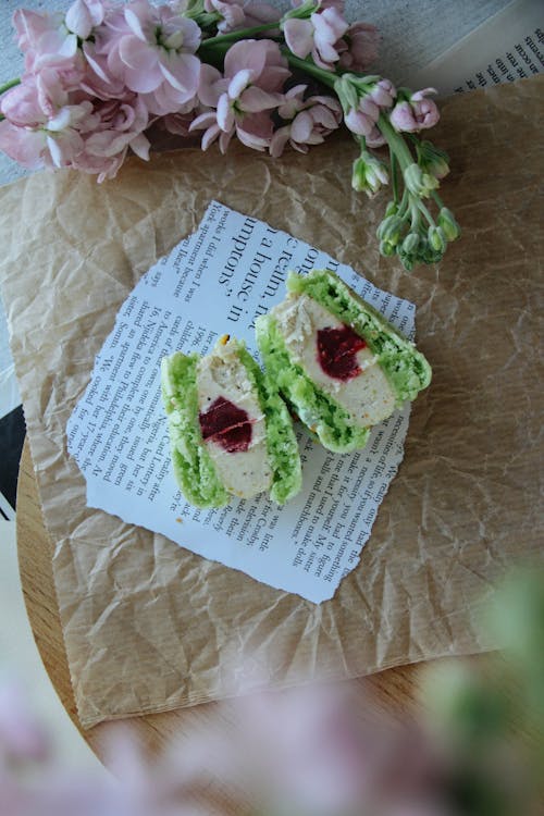 Green Macaron Cut in Half on a Piece of Book Page and Baking Paper