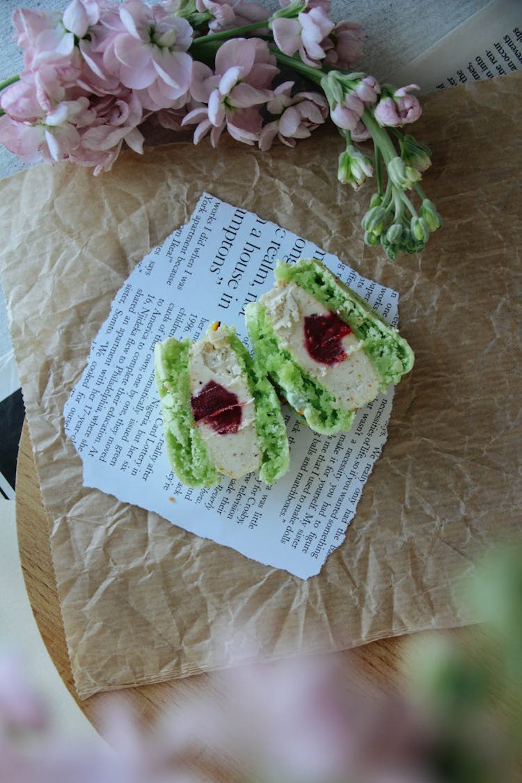 Green Macaron Cut In Half On A Piece Of Book Page And Baking Paper