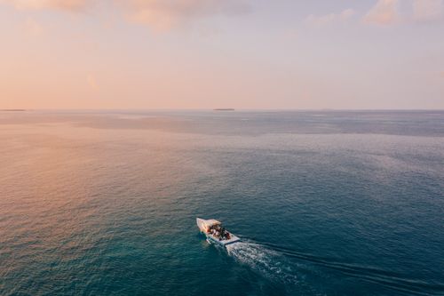 Free A serene sunset over the ocean with a boat sailing, reflecting calm and tranquility. Stock Photo