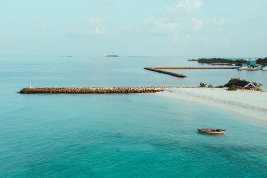 Peaceful tropical island scene with turquoise waters, sandy beach, and a wooden pier.