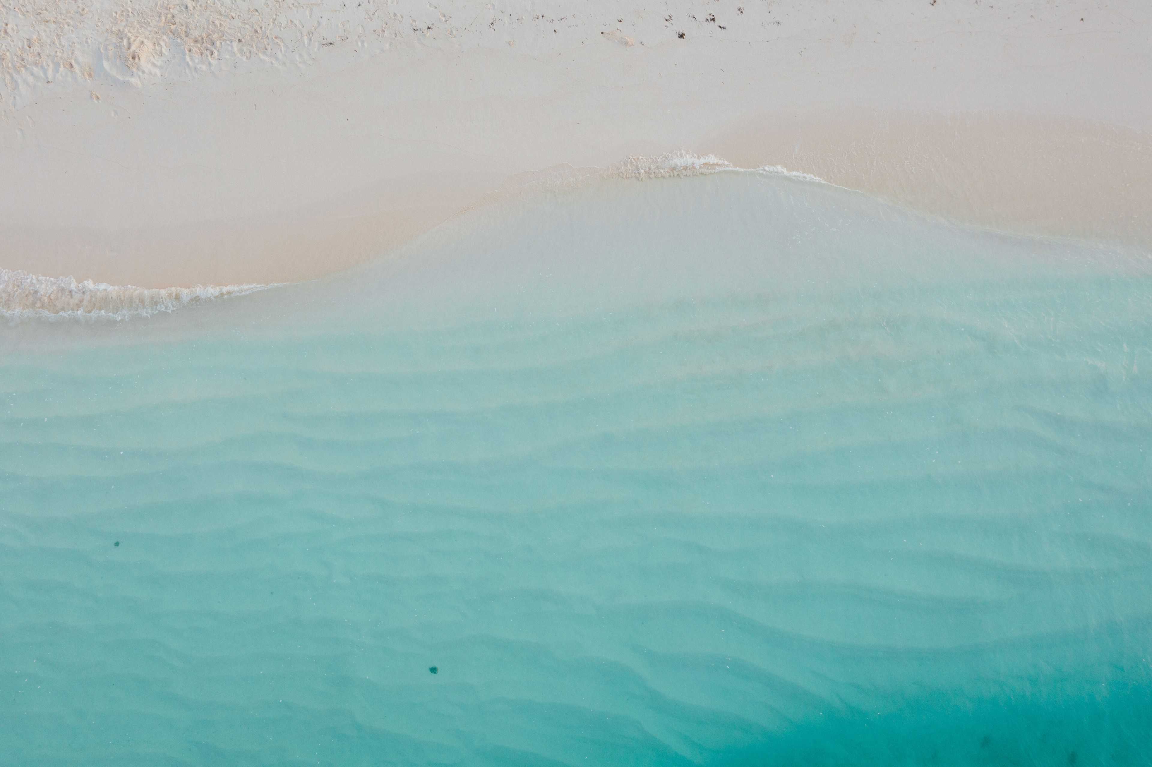 Clear turquoise water washing onto pale sand