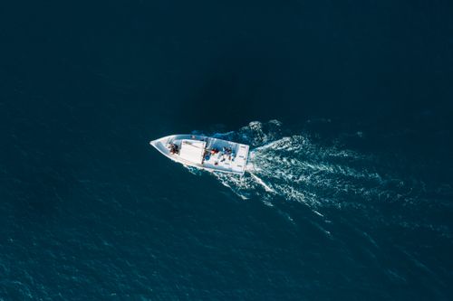 Free A boat cruising through the deep blue sea, viewed from above, offering a sense of adventure and tranquility. Stock Photo