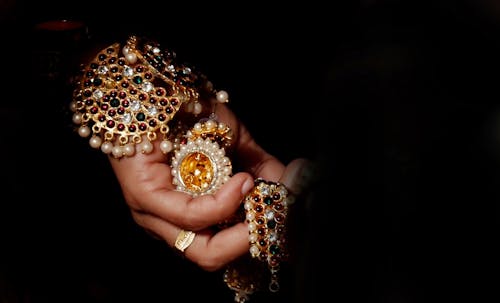 Person Holding Gold-colored and White Jewelry