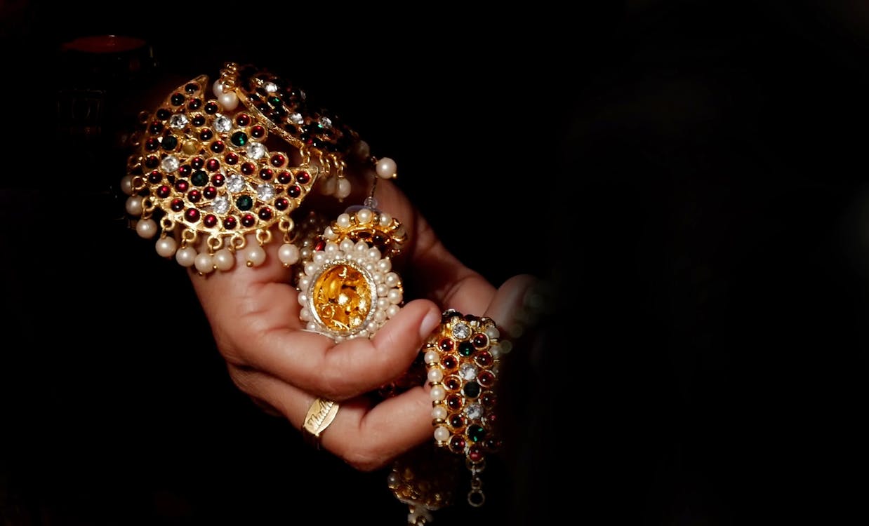 Person Holding Gold-colored and White Jewelry