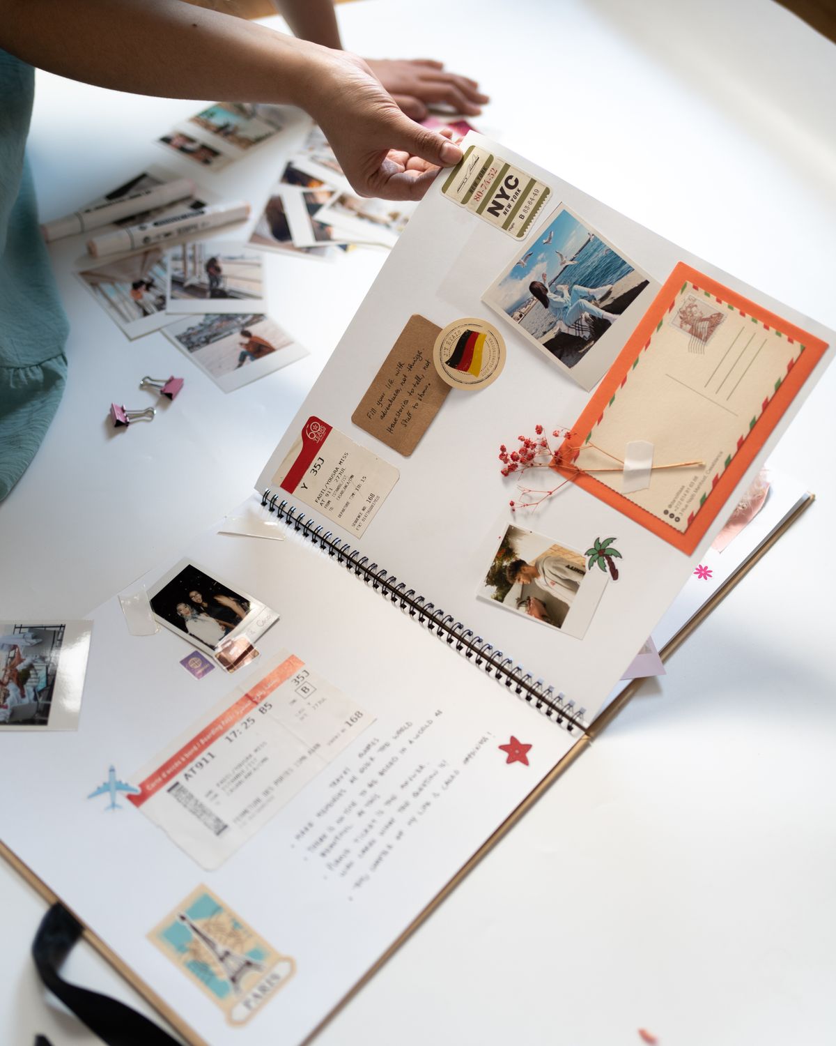Person arranging photographs and postcards in a scrapbook