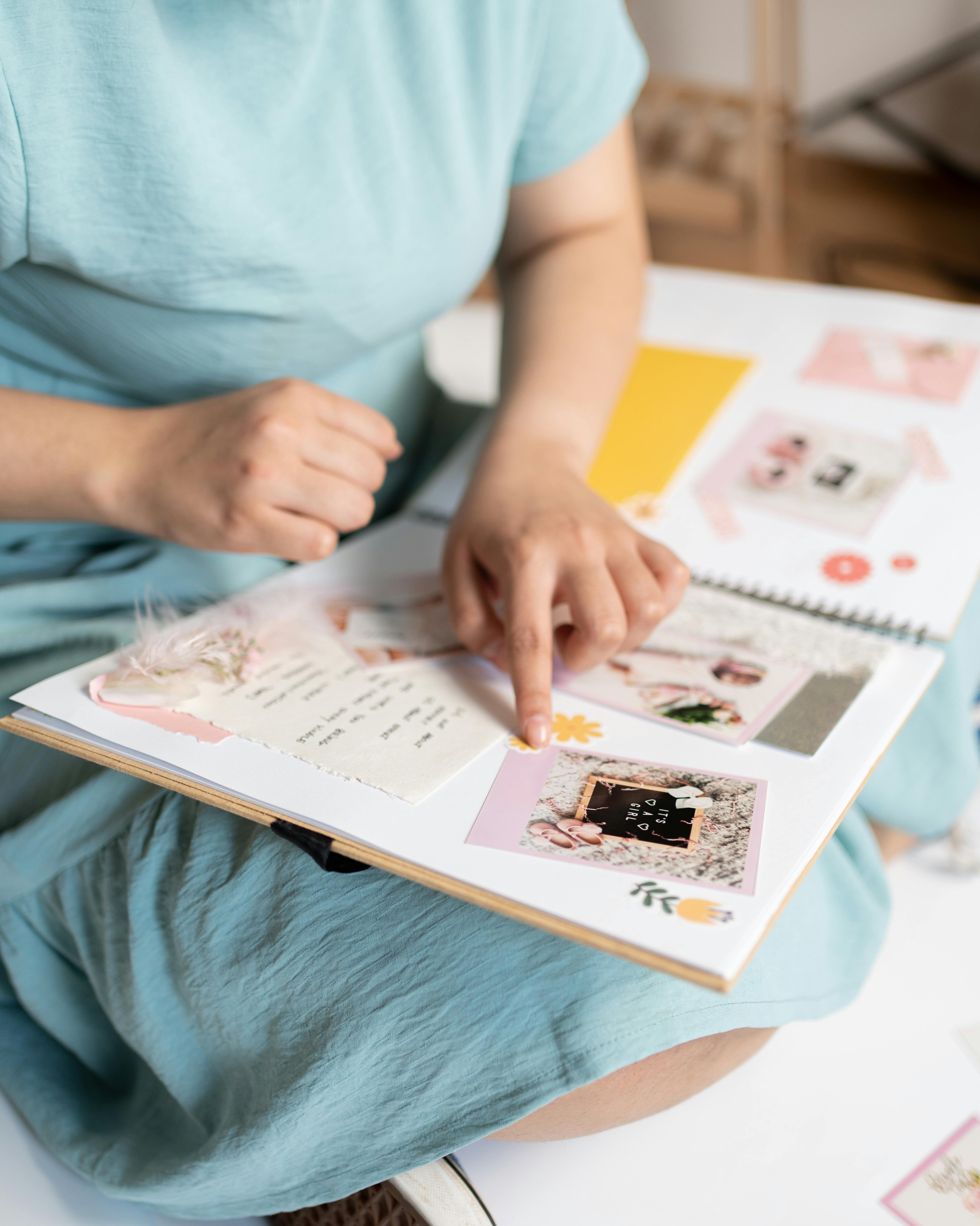 Woman engaged in scrapbooking, crafting a personalized photo album indoors.