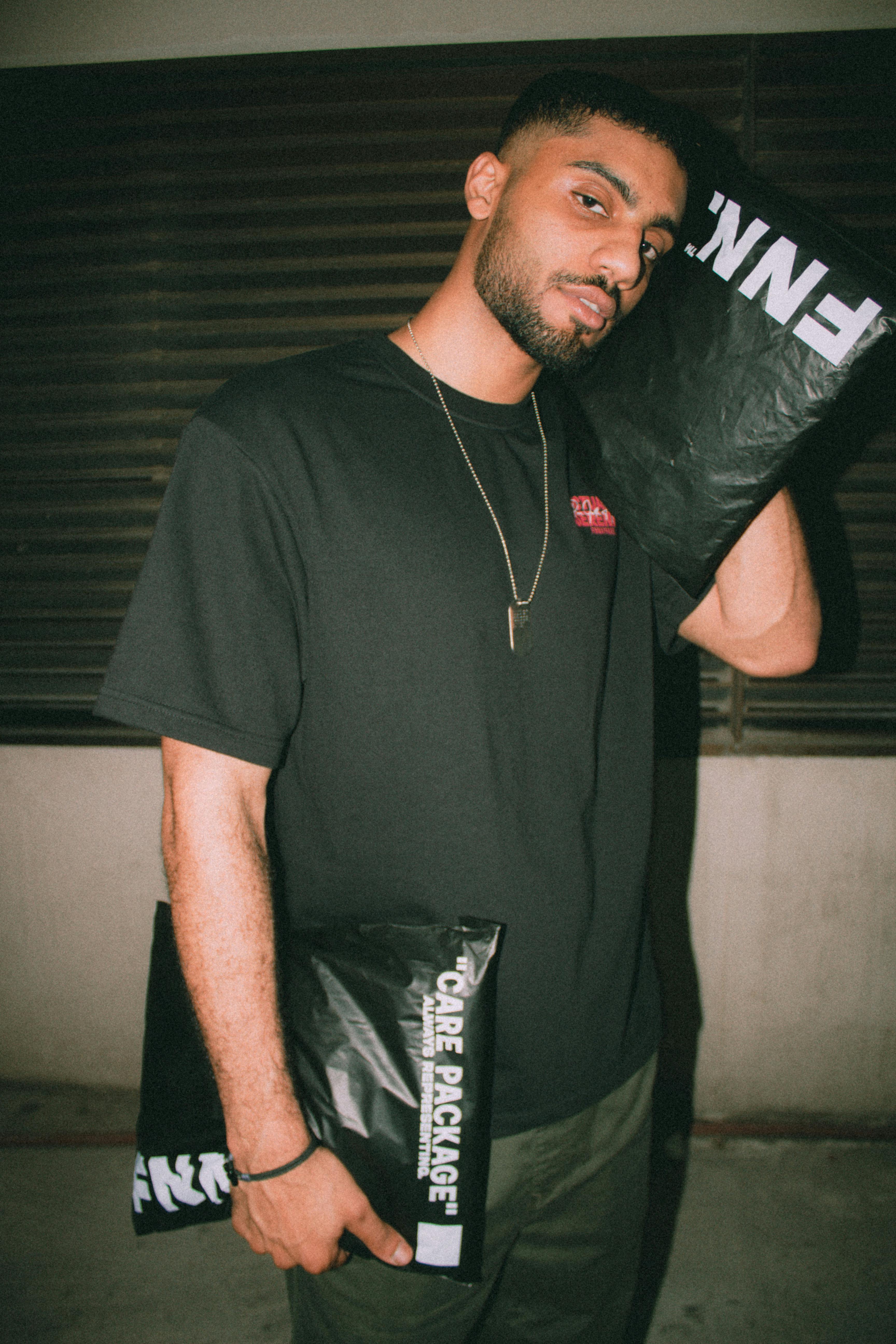 Stylish man posing with branded delivery bags at night.