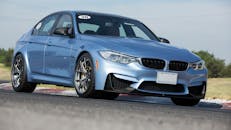 一辆时尚的蓝色豪华轿车白天在停机坪赛车场上巡航