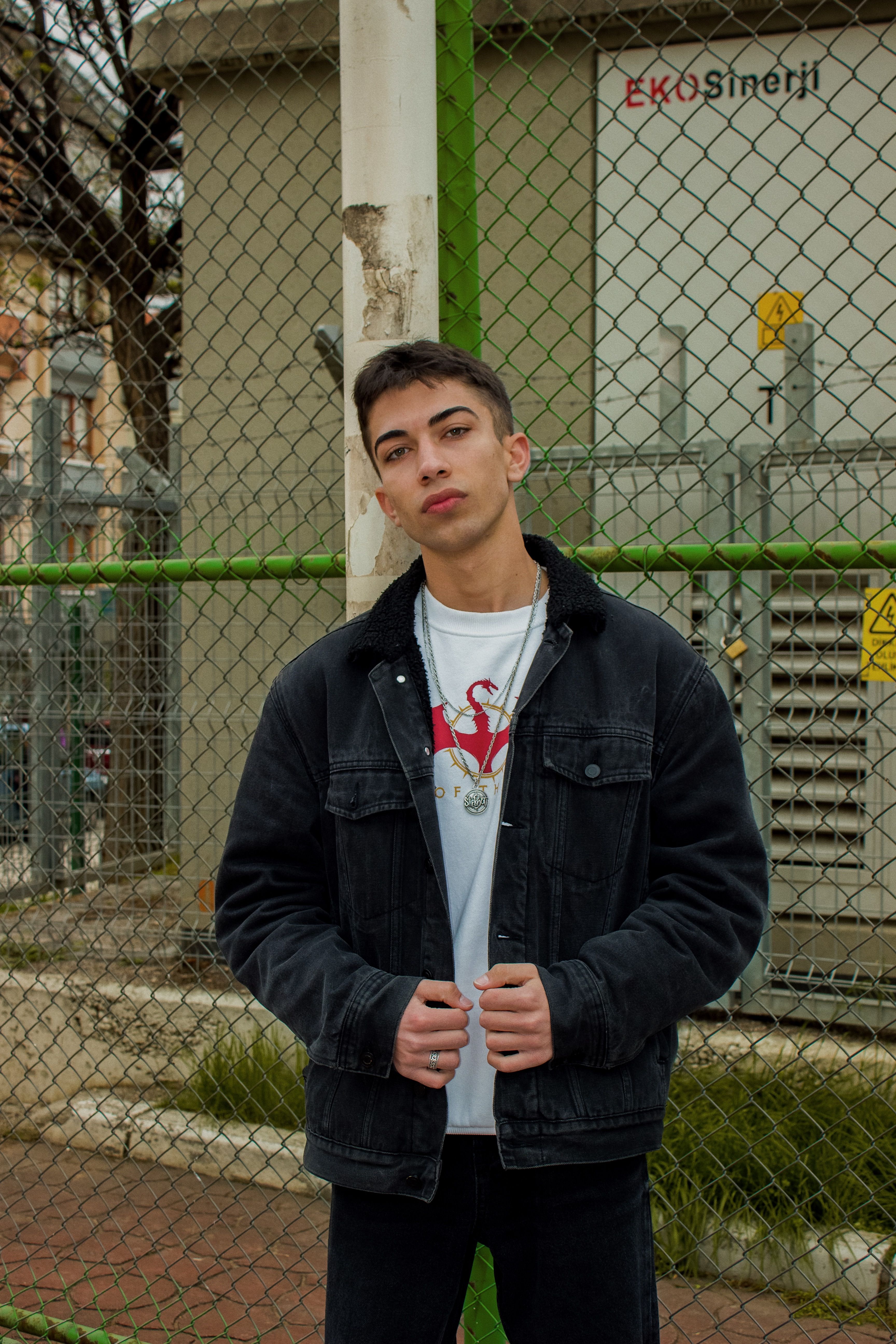 Stylish young man poses in front of a fence in Ankara, adding urban flair to the scene.