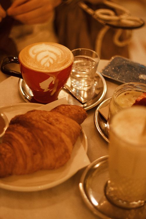 Free Warm cafe scene with a latte and croissant on a table, perfect for a delicious breakfast. Stock Photo