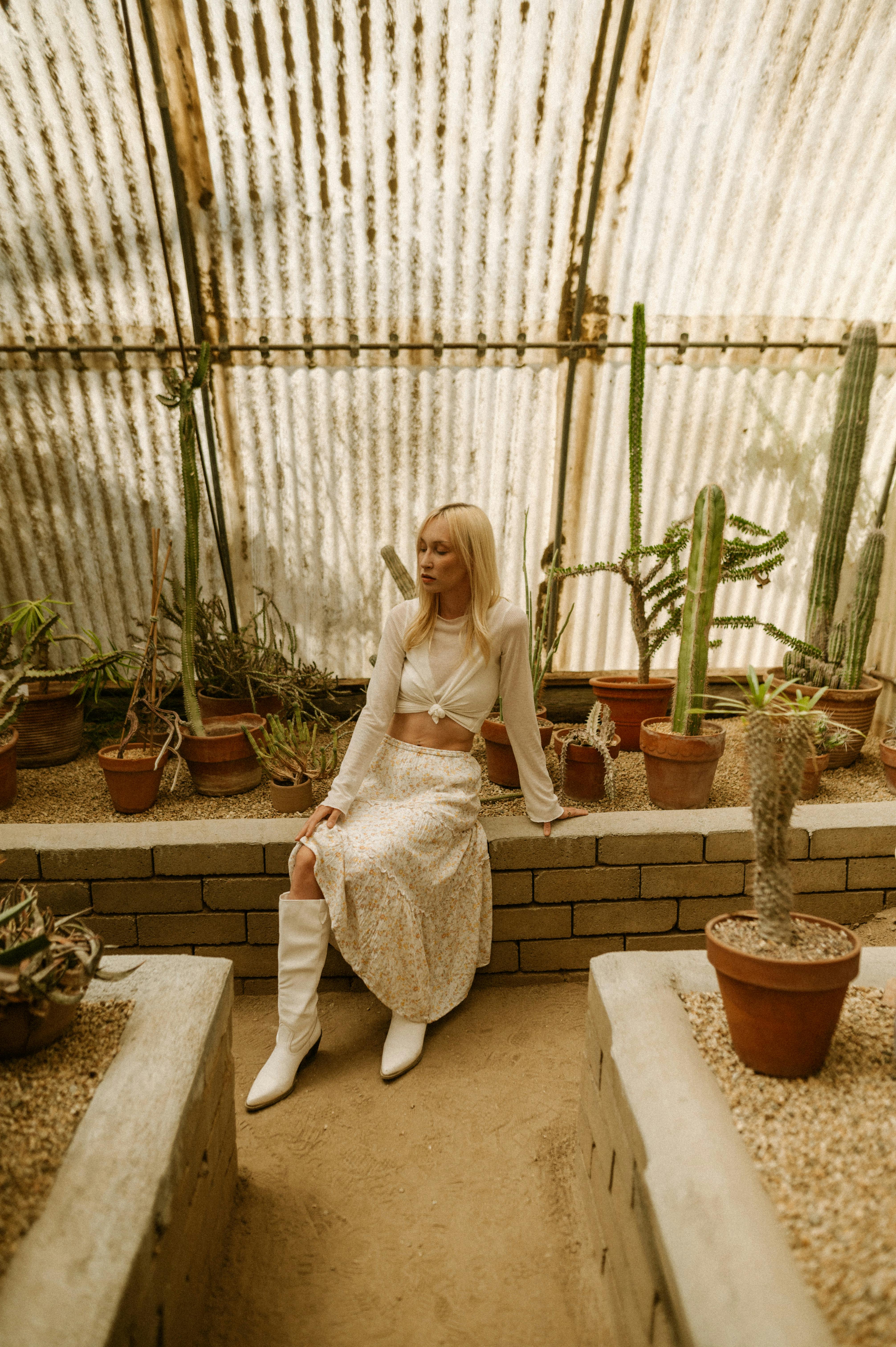 young woman in a white outfit posing in a greenhouse