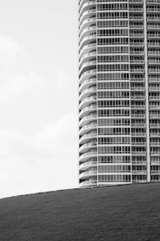 Black and white photo of a modern skyscraper set against a clear sky, showcasing urban architecture.