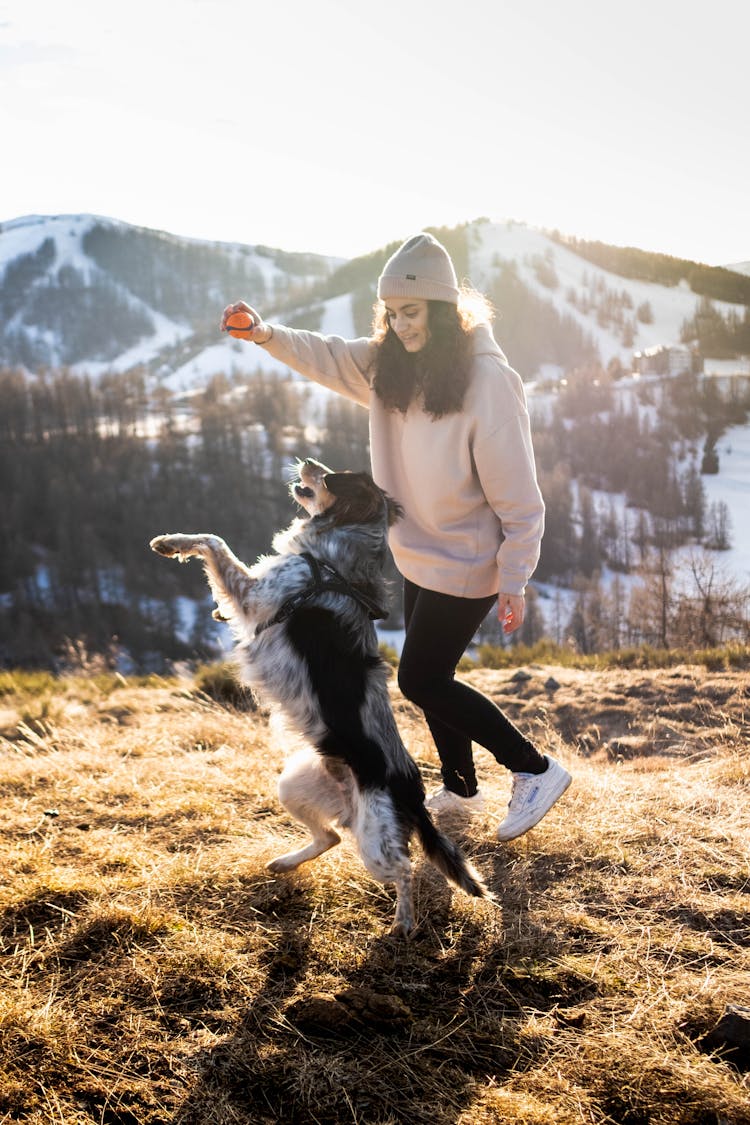 Woman Playing With Her Dog Outdoors In Winter 