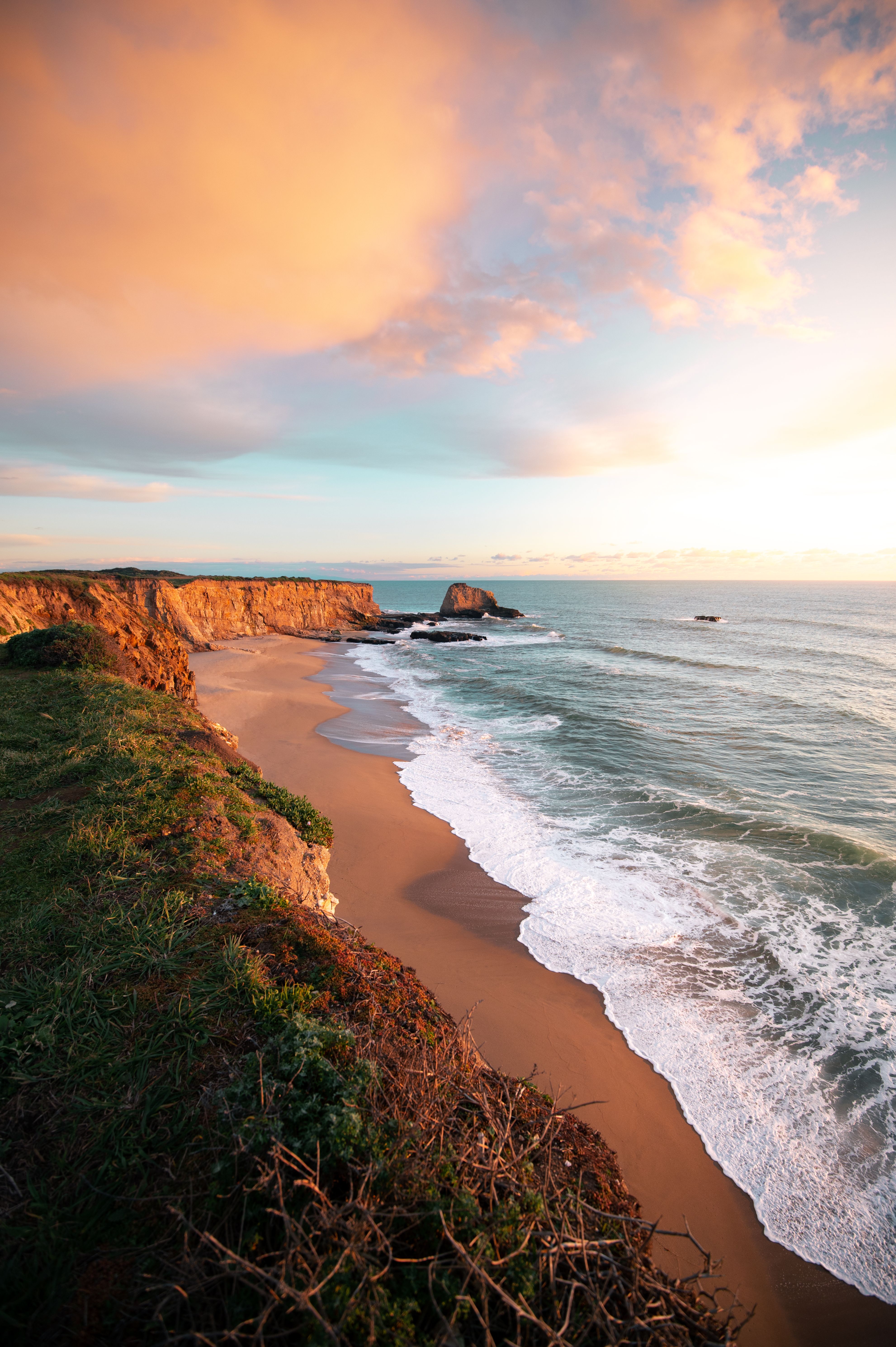 Breathtaking view of Santa Cruz cliffs and ocean waves during a colorful sunset.