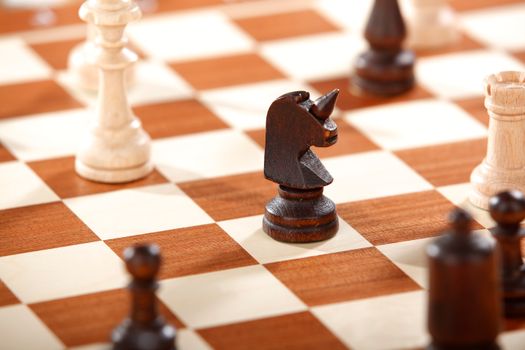 Detailed shot of wooden chess pieces on a classic checkerboard, featuring a knight prominently.
