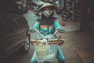 一位戴着口罩的亚洲女子，在繁华的街道上骑着自行车，展现了城市生活