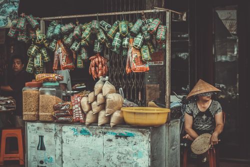 Free A vibrant street market stall featuring traditional Asian foods and local merchants in an urban setting. Stock Photo