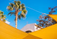 户外场景充满活力，以教堂立面、棕榈树和亮黄色织物为特色，映衬着清澈的蓝天