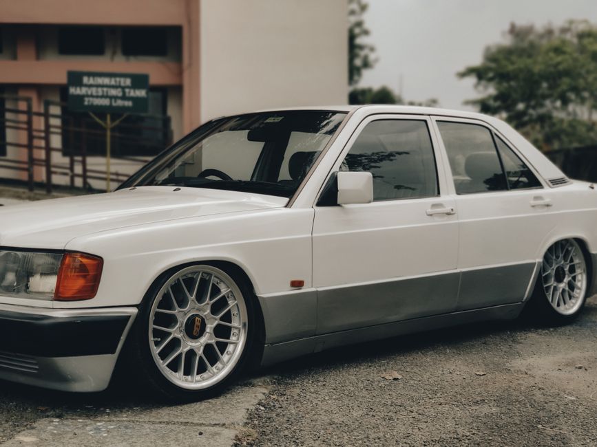 Classic Mercedes W201 parked outdoors showcasing vintage design and white livery.