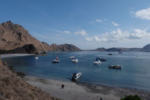 Boats anchored in a serene bay with mountainous backdrops at Padar Island, Indonesia.