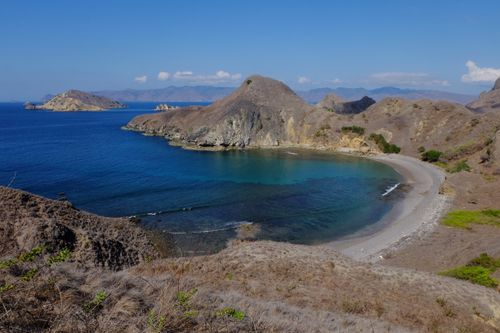 Free Stunning coastal landscape of Padar Island with clear blue waters and rugged hills under a bright sky. Stock Photo