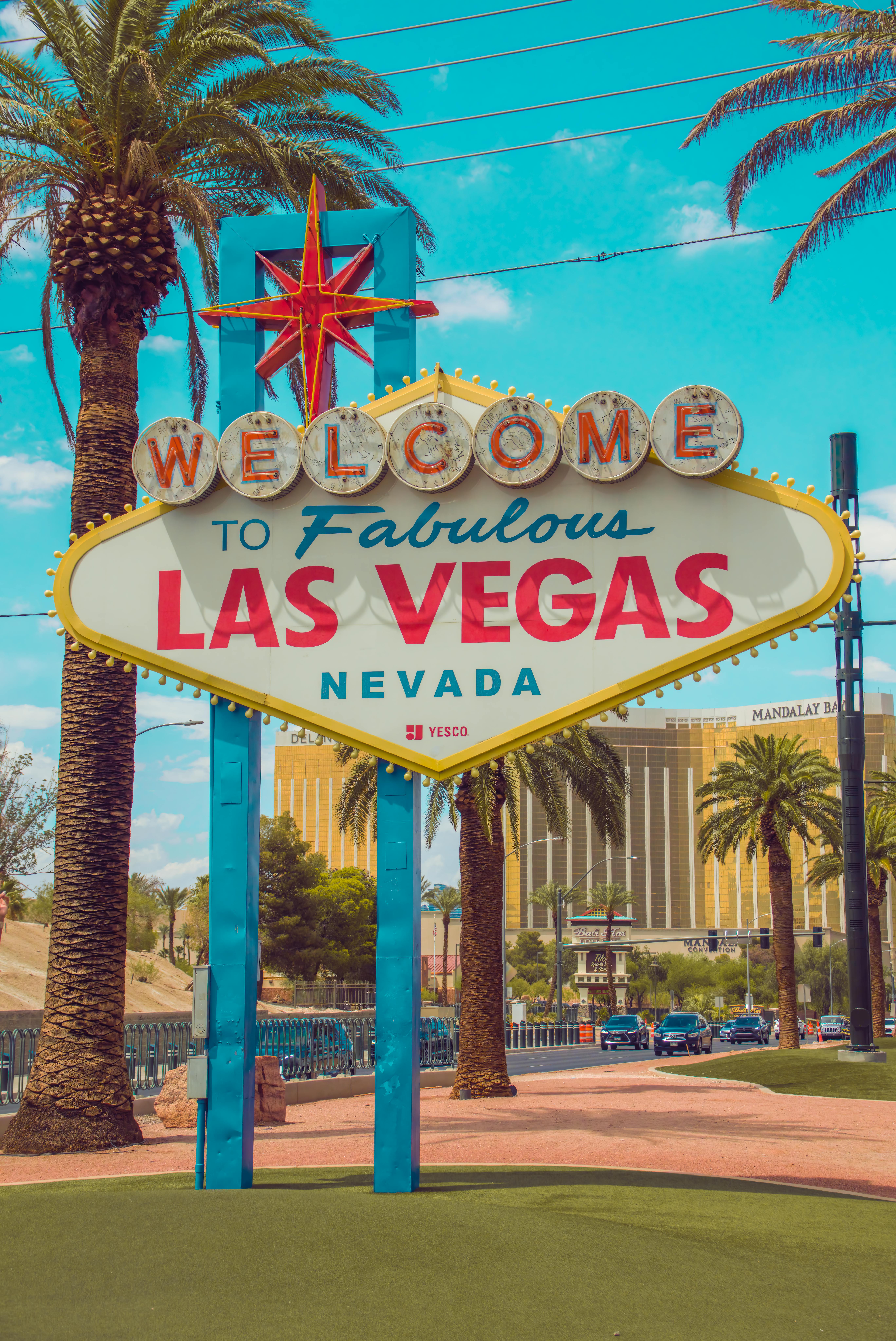 Free Famous Welcome to Fabulous Las Vegas sign with palm trees under a blue sky. Stock Photo