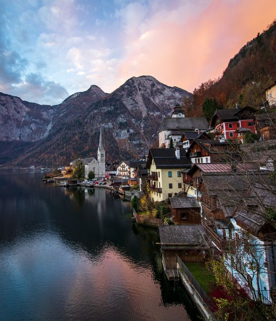 Picturesque sunset over the charming village of Hallstatt with mountains and lake reflection.
