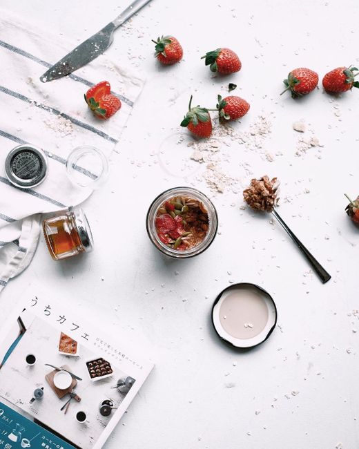 Top view of strawberries and granola on a scattered tabletop, perfect for food photography.