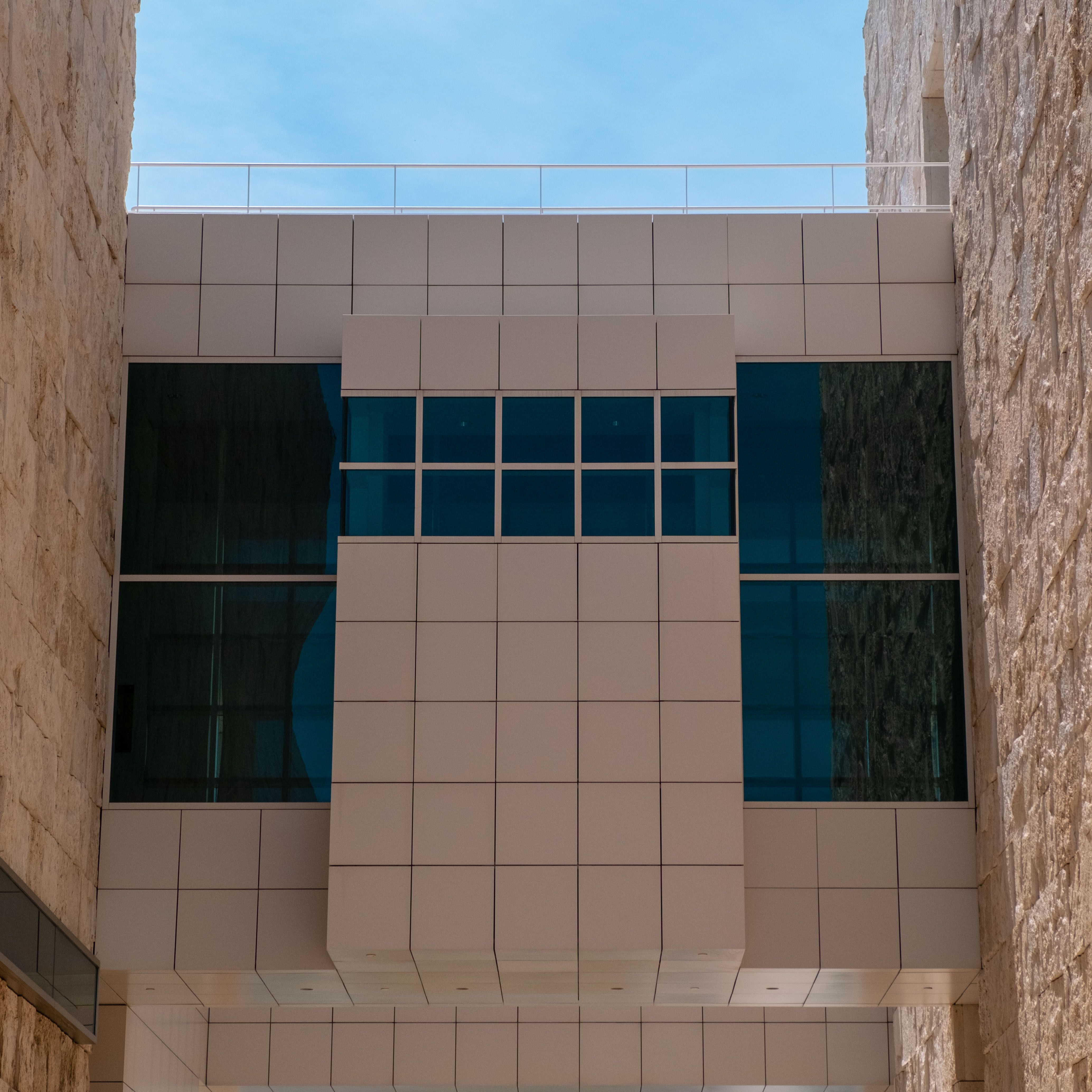 Close-up of a modern building facade featuring reflective blue windows and stone textures.