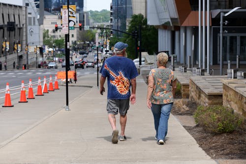 Back View of Woman and Man Walking on Sidewalk