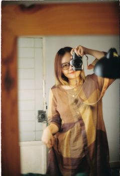 Stylish young woman capturing a mirror selfie at home, embracing a casual fashion style.