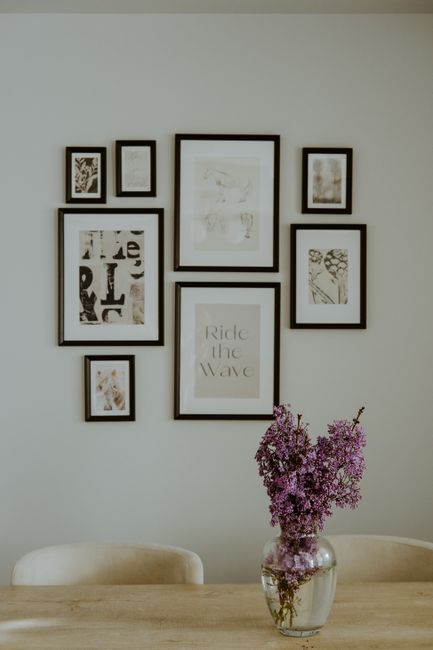 A tastefully arranged dining room with lavender blooms and art on the wall.