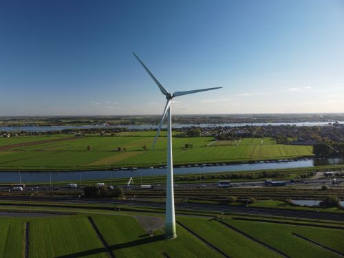 Free A scenic aerial view featuring a wind turbine in lush green farmland, showcasing renewable energy. Stock Photo