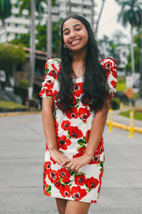 Young Woman in a Dress with a Floral Pattern Standing on the Street 