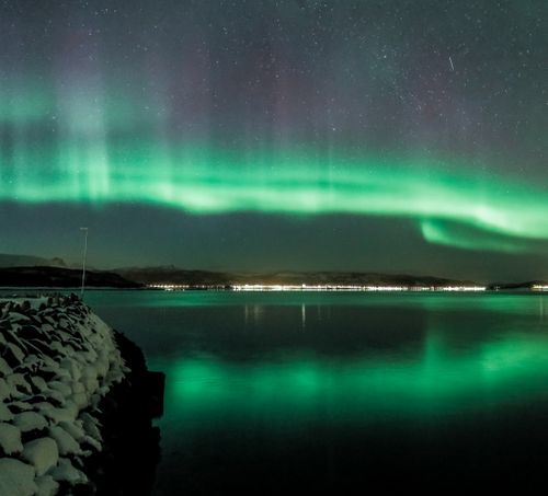 Free Vibrant aurora borealis reflecting in a tranquil lake under starry night sky. Stock Photo
