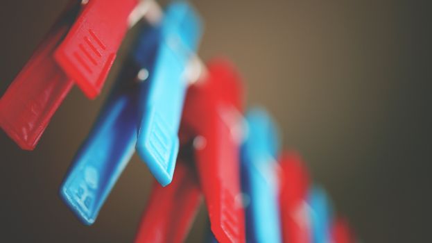 Close-up photo of red and blue plastic clothespins with bokeh effect.