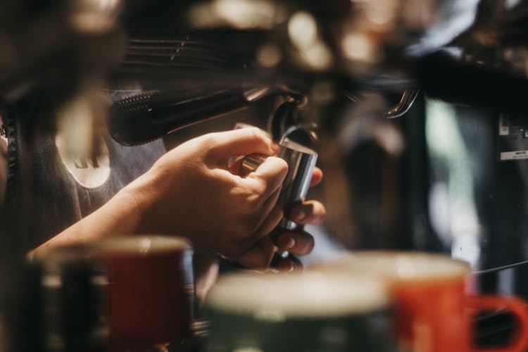 Hand Holding Cup Under Coffee Machine