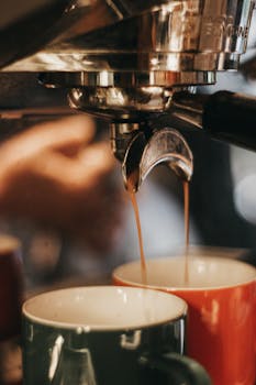 Close-up of an espresso machine pouring coffee into two mugs, highlighting the brewing process.