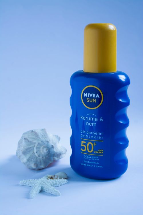 Free Nivea Sun SPF 50+ lotion with seashells on a blue backdrop, ideal for summer skincare. Stock Photo
