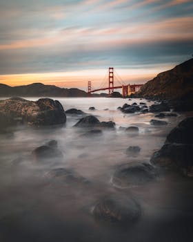 黄昏时分，旧金山的金门大桥风景中，海浪与岩石笼罩在薄雾里