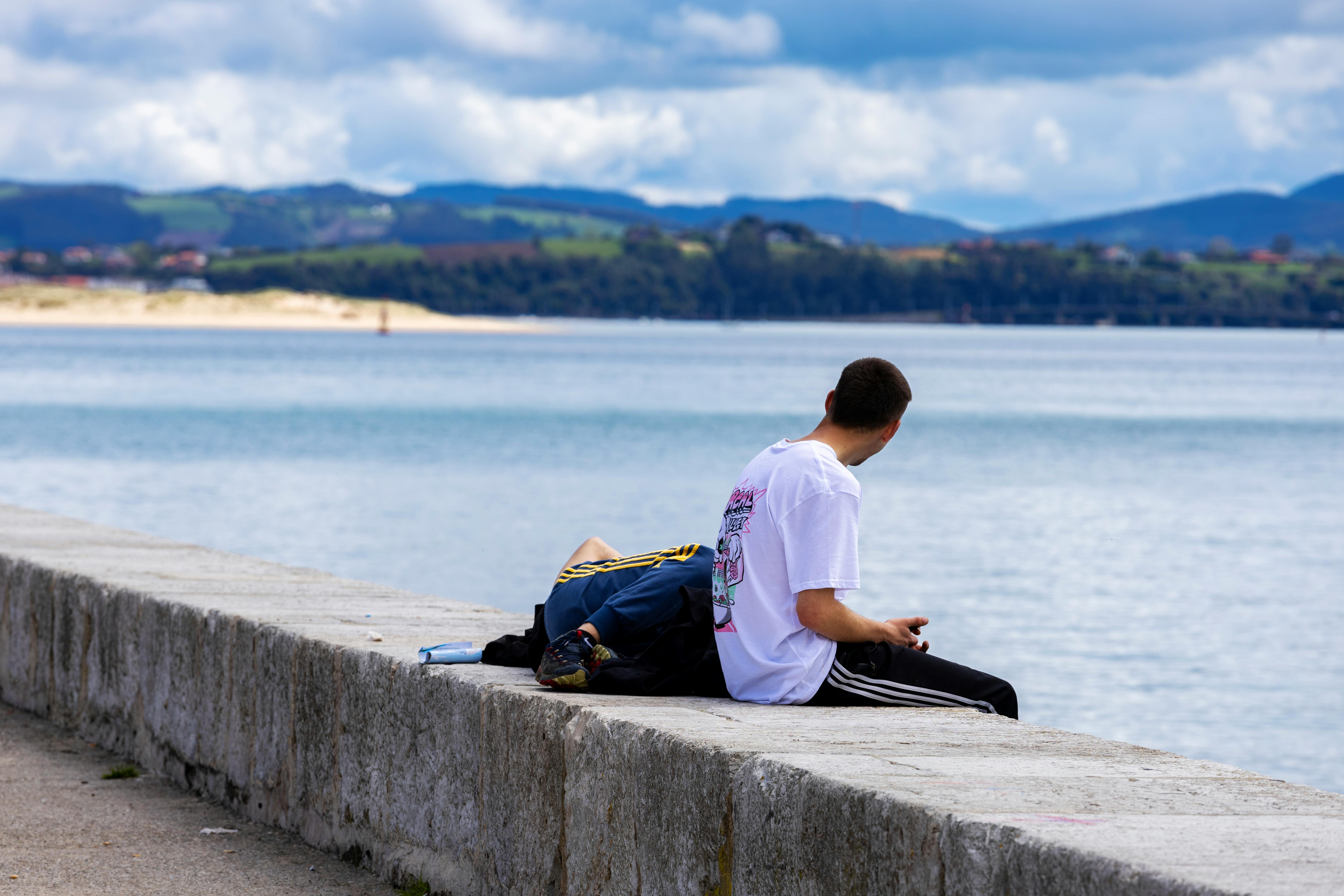 a man sitting on a concrete wall looking out to sea