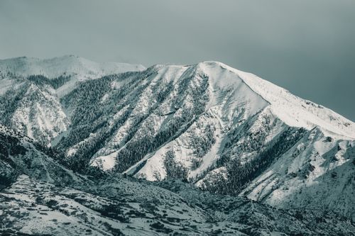 Free A serene winter view of snow-covered mountains under a gray sky. Stock Photo