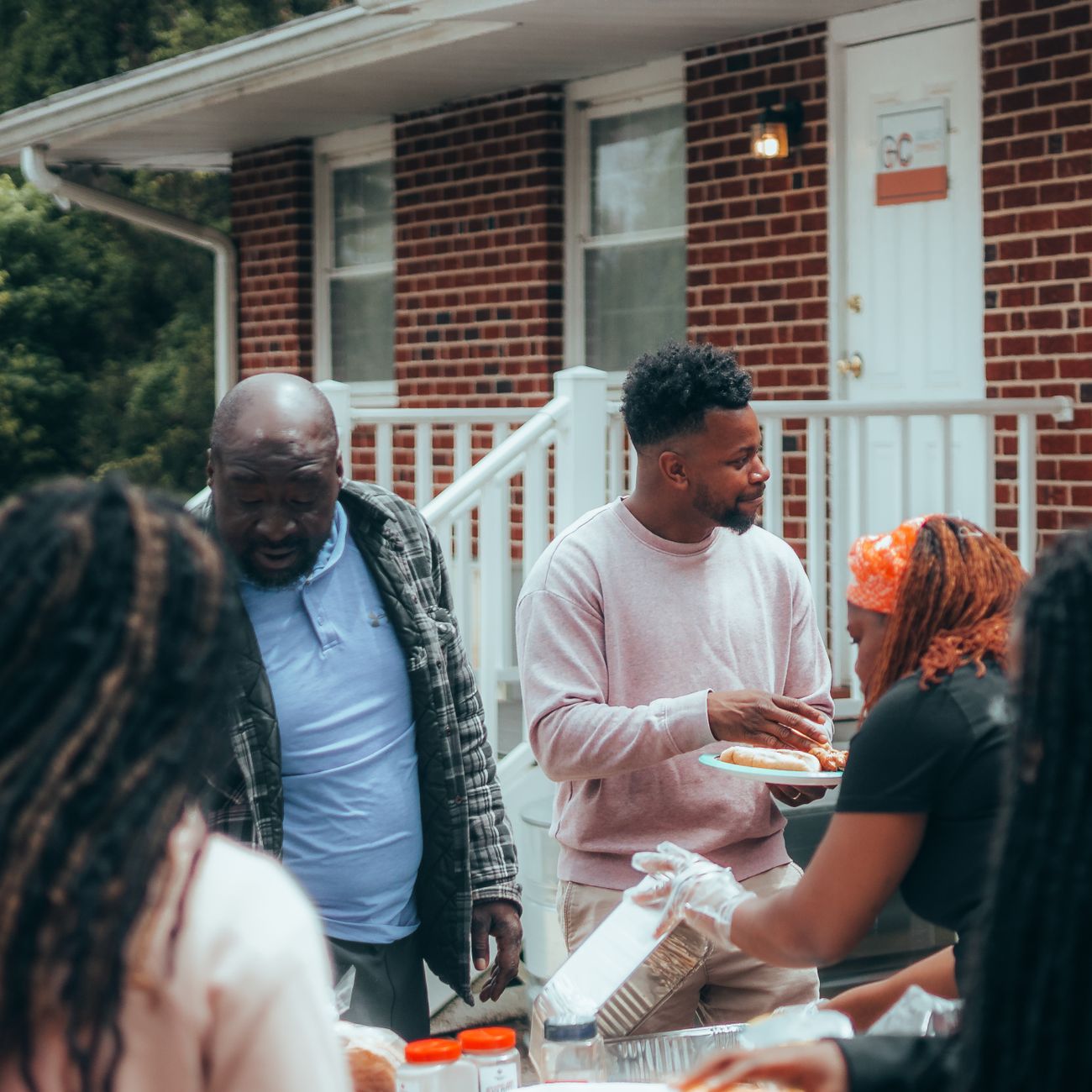 Adults enjoying a casual backyard barbecue gathering in a suburban setting.