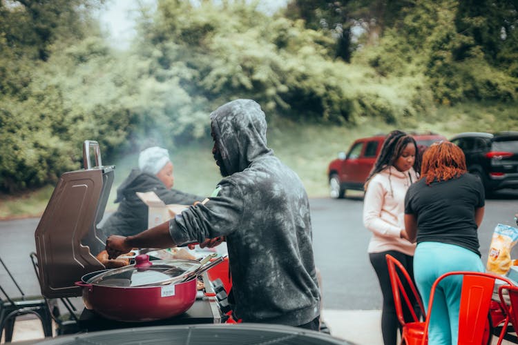 Man Cooking Sausages On The Grill At A Picnic 