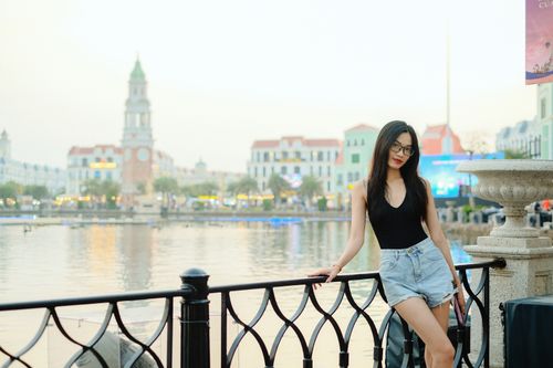 Free Elegant young woman in casual attire by a serene waterfront in Vietnam's urban setting. Stock Photo