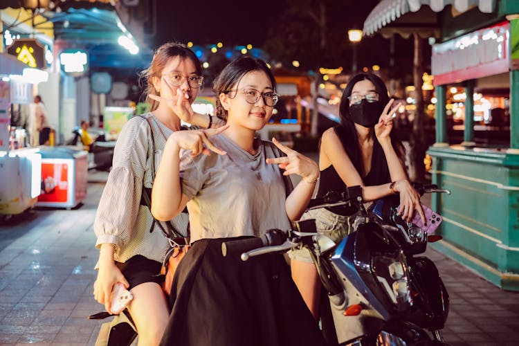 Women Posing On Scooters On Street Market At Night