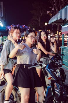 Three young women pose confidently on scooters, embracing city nightlife elegance.