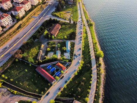 Aerial perspective of a coastal town with buildings, roads, and shoreline greenery.